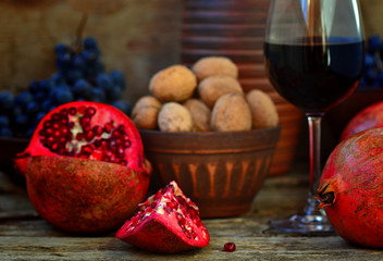pomegranate, walnuts and glass of wine on a wooden background