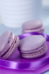Obraz na płótnie Canvas Three violet French macaroons cookies and ribbon