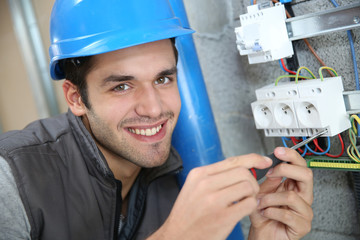 Young electrician working on building site