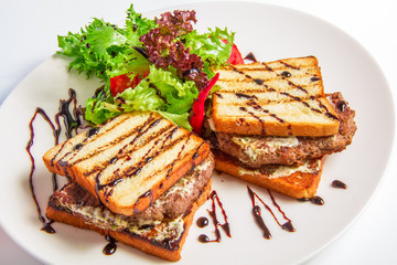 Hamburger closeup with bacon and cheese sauce, salad, olive