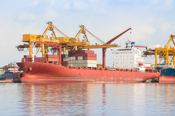 Naklejka premium Gantry crane loading and unloading cargo container from cargo ship at port to show global international logistics and transportation by cargo ship and cargo container, Logistic import export concept.