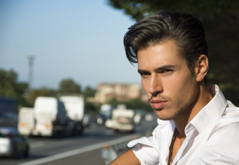 Handsome young man and busy road with traffic