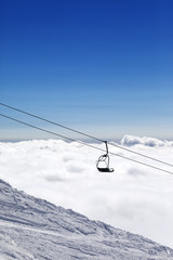 Ski slope, chair-lift and mountains under clouds