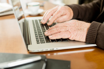 Senior working with Laptop, focus on hands