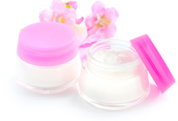 Cosmetic creams and pink flowers isolated on white background