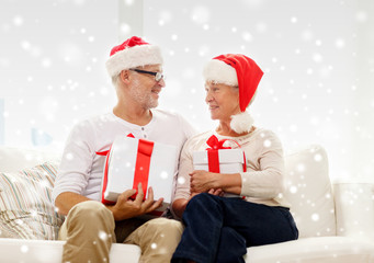 happy senior couple in santa hats with gift boxes