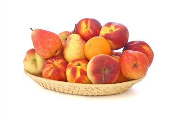 Peaches, oranges and pears in a wicker plate isolated on white