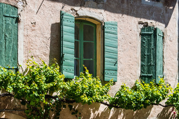 Stone building with green wooden shutters.