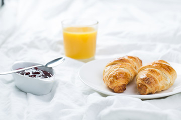 delicious breakfast with croissants in bed