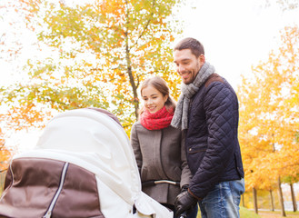 smiling couple with baby pram in autumn park