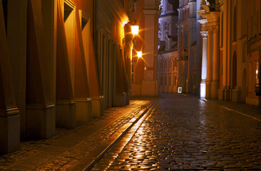 A church and cobbled street at night in Poznan .
