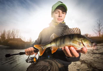 Fototapeten Happy angler with perch fishing trophy © vitaliy_melnik