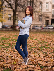 Redhead girl standing and holding a book in park