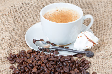 Delicious freshly brewed cup of coffee with whole beans on burla