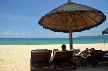 Man and woman on the beach under an umbrella