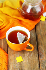 Cup of tea, teapot and tea bags on wooden table close-up