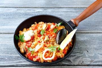 Paella with shrimp, mussels, Lemon and rice in a frying pan