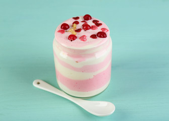 Cranberry milk dessert in glass jar, on color wooden background