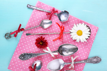 Metal spoons on pink polka dot napkin on wooden background