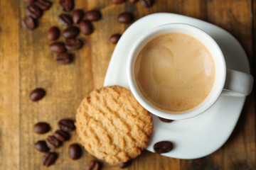 Cup of espresso and tasty cookie on wooden background