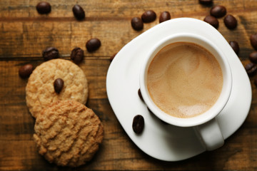 Cup of espresso and tasty cookie on wooden background