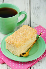 Napoleon cake on plate and cup of tea on table close-up