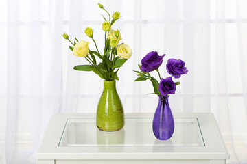 Beautiful bouquet of flowers in vases on window background
