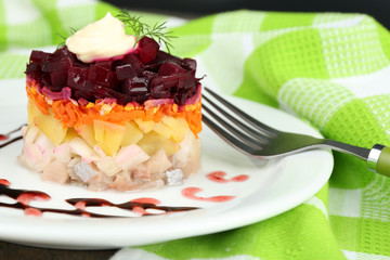 Russian herring salad on plate on wooden table background