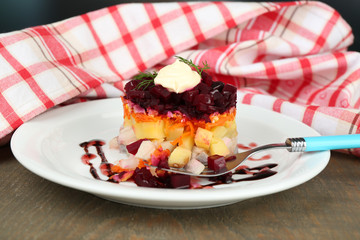 Russian herring salad on plate on wooden table background