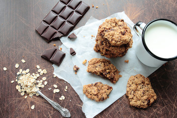 Crunchy oat cookies with dark chocolate and mug of fresh milk