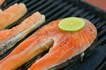 Portion of fresh salmon fillet with lime on a grill