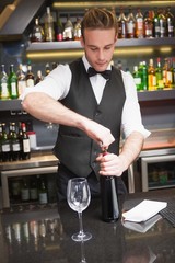Handsome waiter opening a bottle of red wine