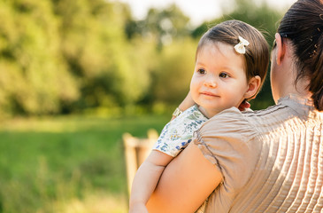 Back view of mother holding baby girl in her arms