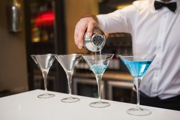Bartender pouring blue alcohol into cocktail glass
