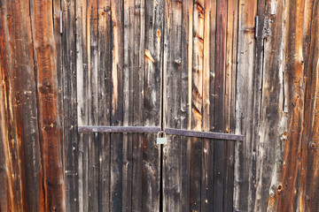 burnt wooden door locked with rusty padlock