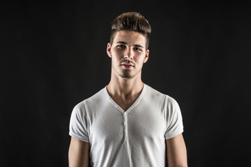 Obraz premium Portrait of confident young man wearing white shirt against blac