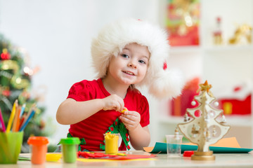 kid in Santa hat making christmas tree of plasticine