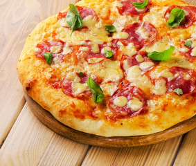 Salami pizza with cheese and basil on  wooden  board.