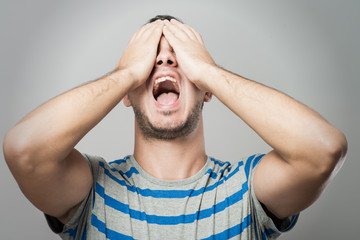 Young Caucasian man hiding his face with hand