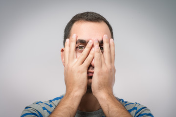 Young Caucasian man hiding his face with hand