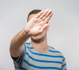 Young Caucasian man hiding his face with hand