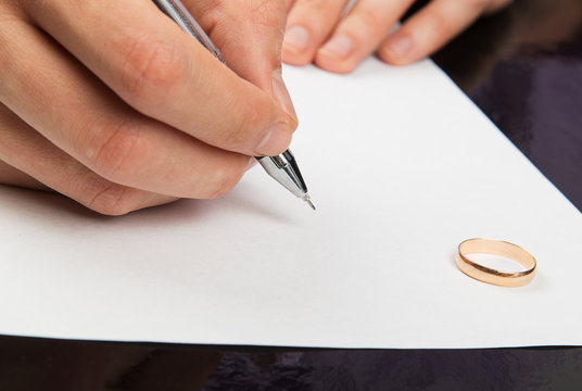 Closeup of male hand signing divorce papers