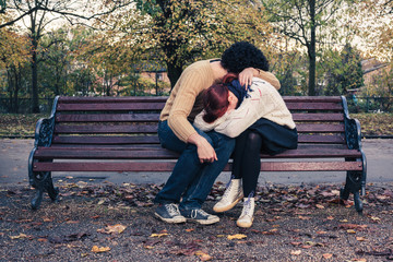 Sad young couple on park bench