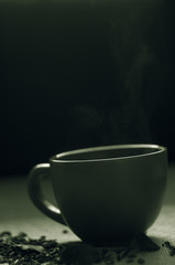 Dry tea with green leaves in cup, on burlap background