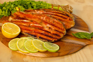 Grilled salmon fillet with lime and parsley on a wooden board