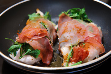Chicken breast wrapped in parma ham with parsley.