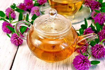 Tea with clover in glass teapot on light board