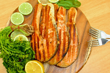 Grilled salmon fillet with lime and parsley on a wooden board