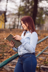 Obraz premium Redhead student girl reading a book in park