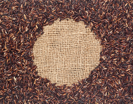 Red rice forming a round frame on burlap fabric